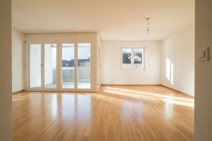 Empty living area of a home with wood floors and patio doors